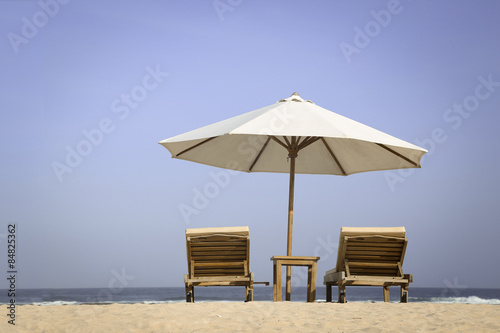 Tropical beach scenery with parasol and chairs 