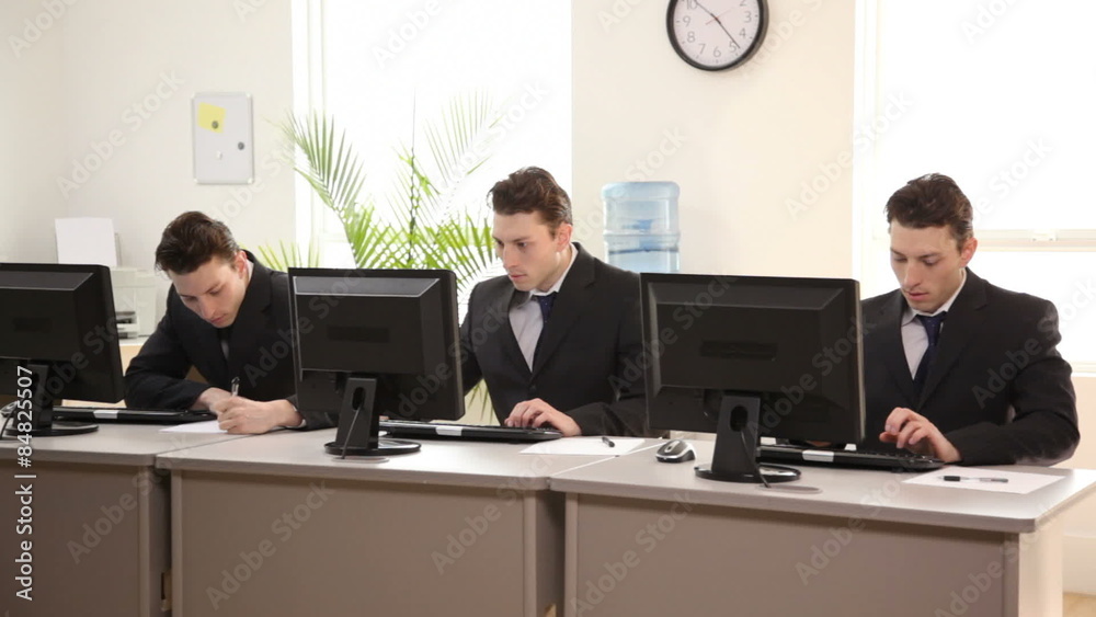 Three identical businessmen working in office Three identical businessmen working in office