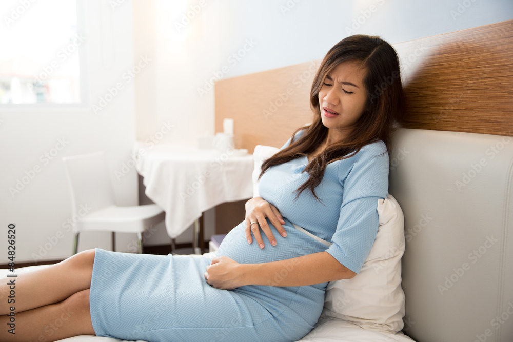 Asian pregnant woman has stomachache sitting on her bed Asian pregnant woman has stomachache sitting on her bed