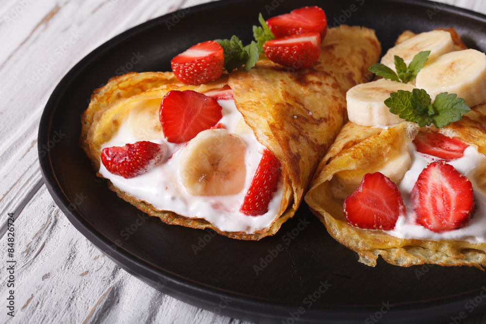 crepes with strawberries, bananas and cream close-up on a plate crepes with strawberries, bananas and cream close-up on a plate