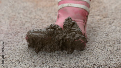 Muddy boot falling onto carpet in slow motion