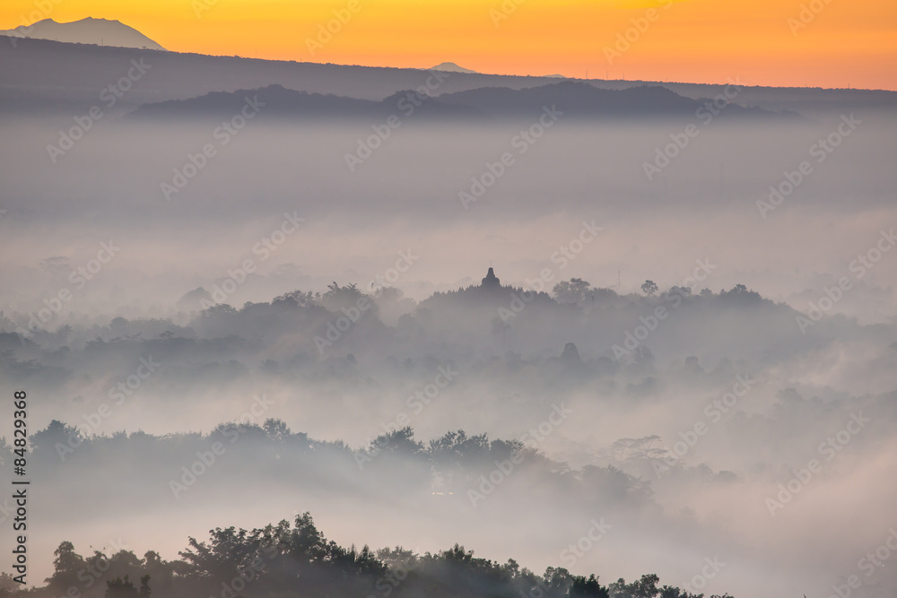 Fototapeta premium Colorful sunrise over Borobudur temple in misty jungle forest, I