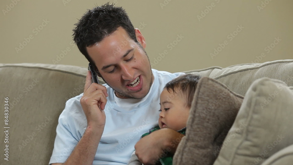 Father talking on cell phone with baby Father talking on cell phone with baby