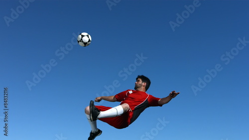 Soccer player kicking ball in mid-air, slow motion
