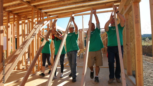 Volunteers working together lifting wall