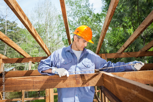 Construction Worker Measuring Timber Frame