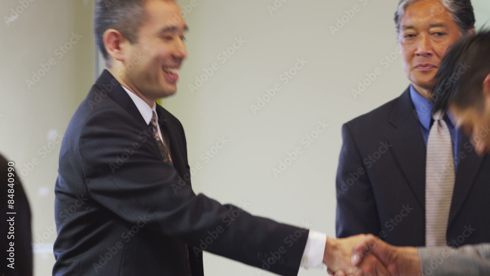 Group of Asian businesspeople shake hands and bow