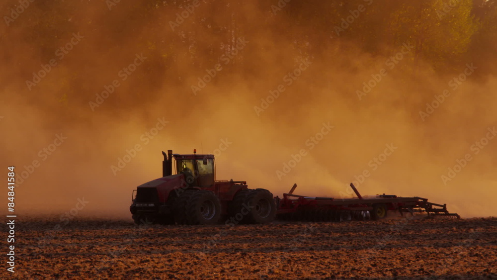 Tractor plowing field at sunset Tractor plowing field at sunset