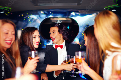 group of happy elegant women clinking glasses in limousine, hen party