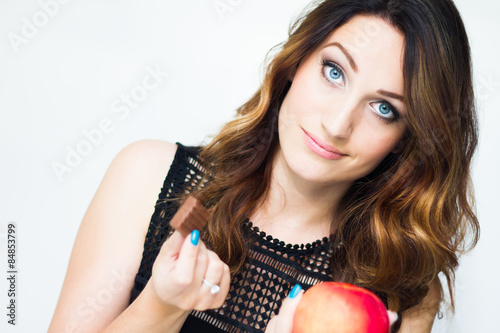 Young beautiful girl making choice between chocolate and apple.