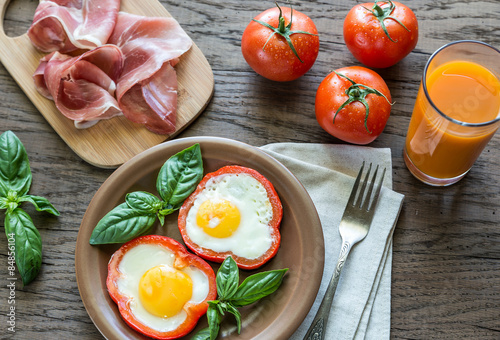 Fried eggs with prosciutto on the wooden table