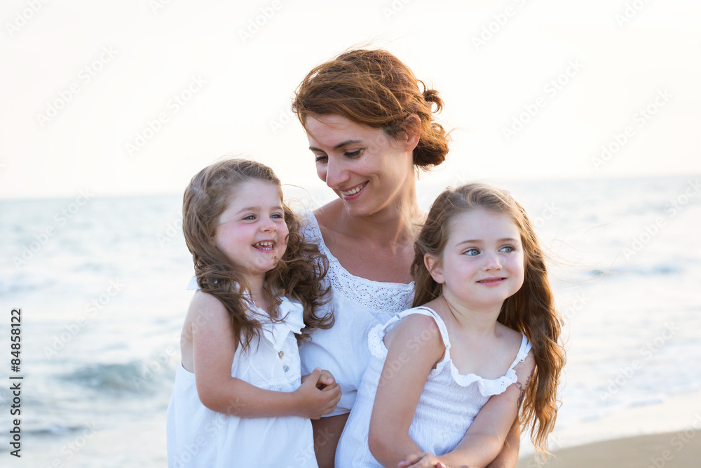 Close-up portrait of mother with daughters smiling on the beach