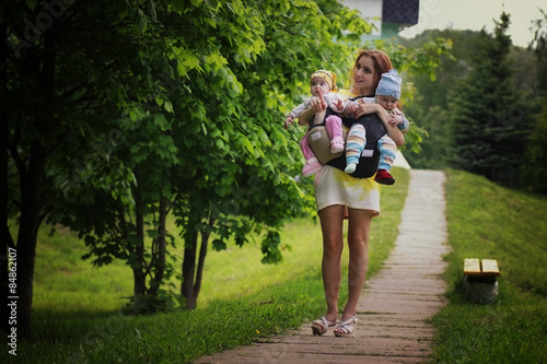 Fototapeta Naklejka Na Ścianę i Meble -  young mom girl walks twins