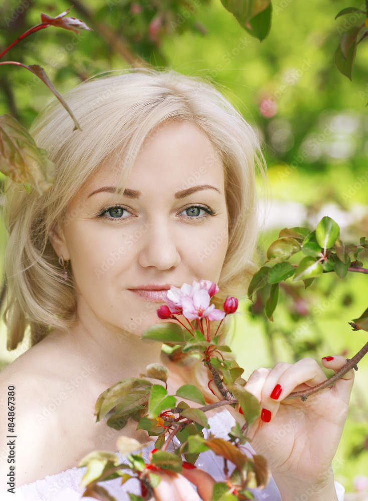 Fototapeta premium Girl holding blossoming branch of an apple tree