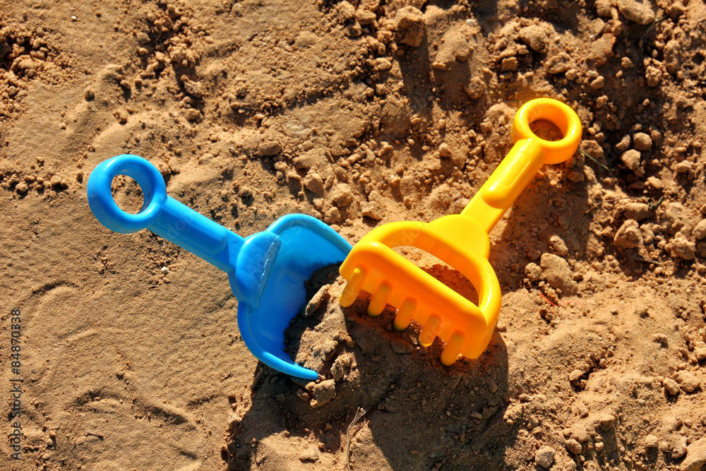 Blue childrens spatula and yellow rake, stuck in sand Blue childrens spatula and yellow rake, stuck in sand