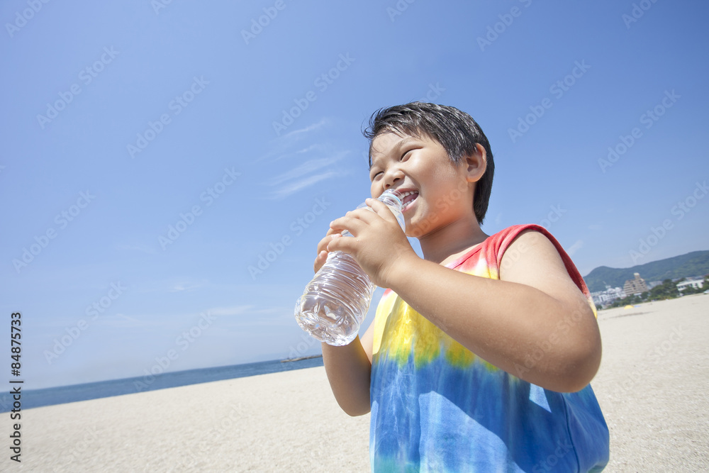青空とビーチと水を飲む子供