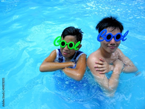 Two young boys in a swimming pool with funny shades