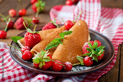 Pancakes with berries and syrup in a rustic style