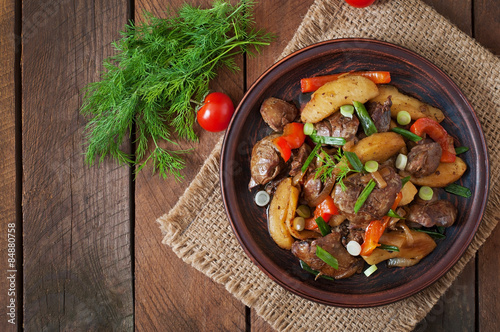 Roast chicken liver with vegetables on wooden background