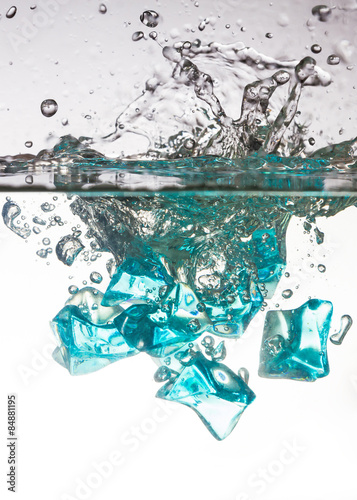blue ice cubes dropped into water with splash 