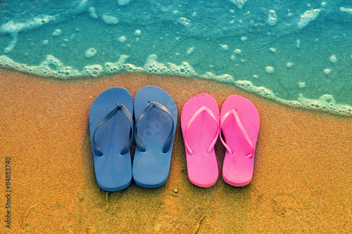 Romantic beach scene. Female and male flip flpp sandals on the beach
