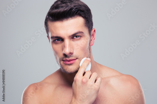 Man cleaning face skin with batting cotton pads photo