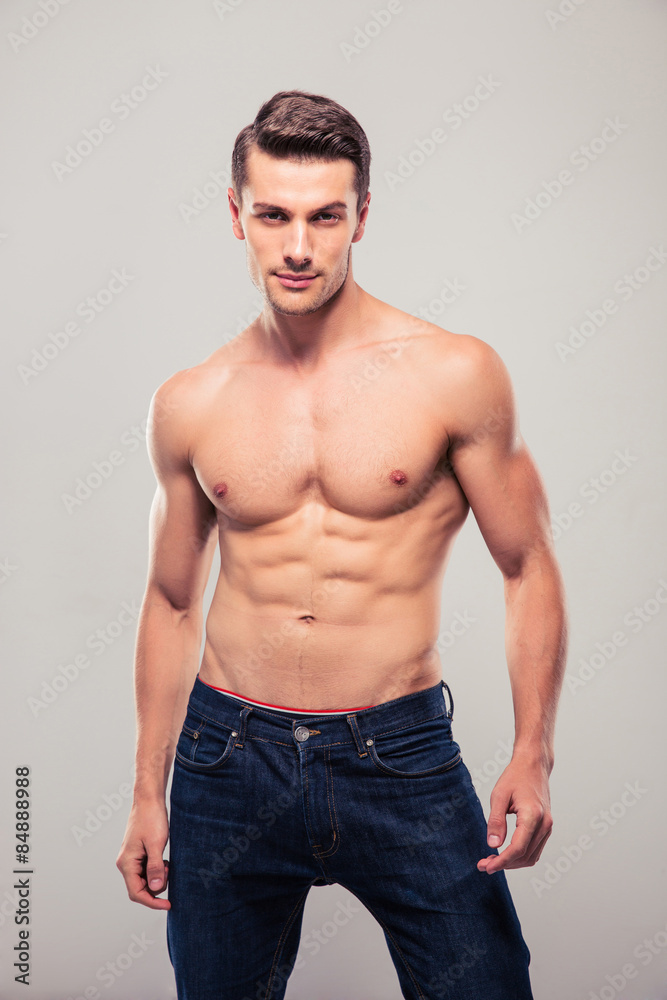 Sexy confident man posing over gray background