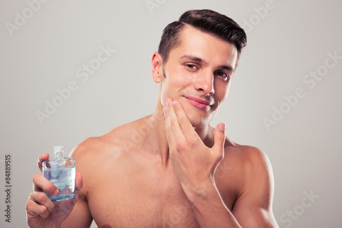 Bilde på lerret Man applying lotion after shave on face
