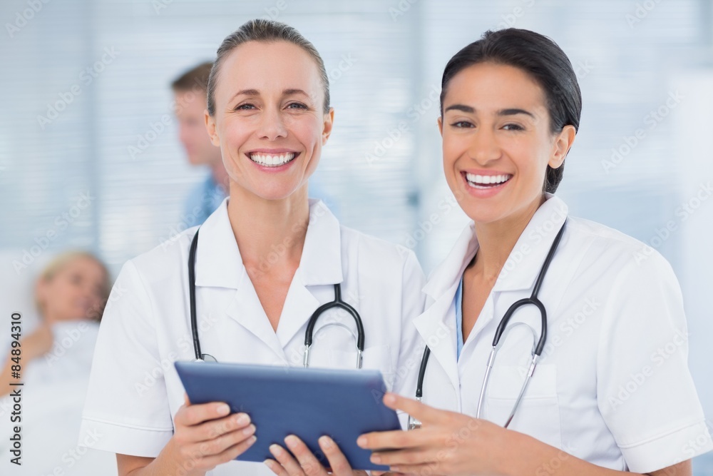 Happy doctors looking at clipboard while theirs colleagues speak Happy doctors looking at clipboard while theirs colleagues speak
