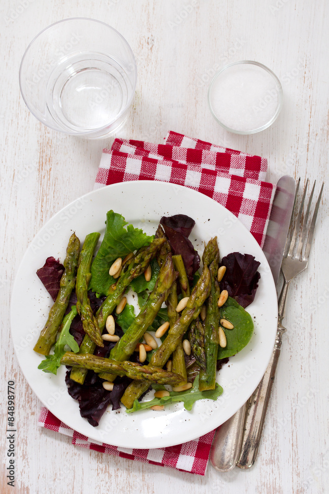 salad asparagus and pine nuts in white plate with glass of water