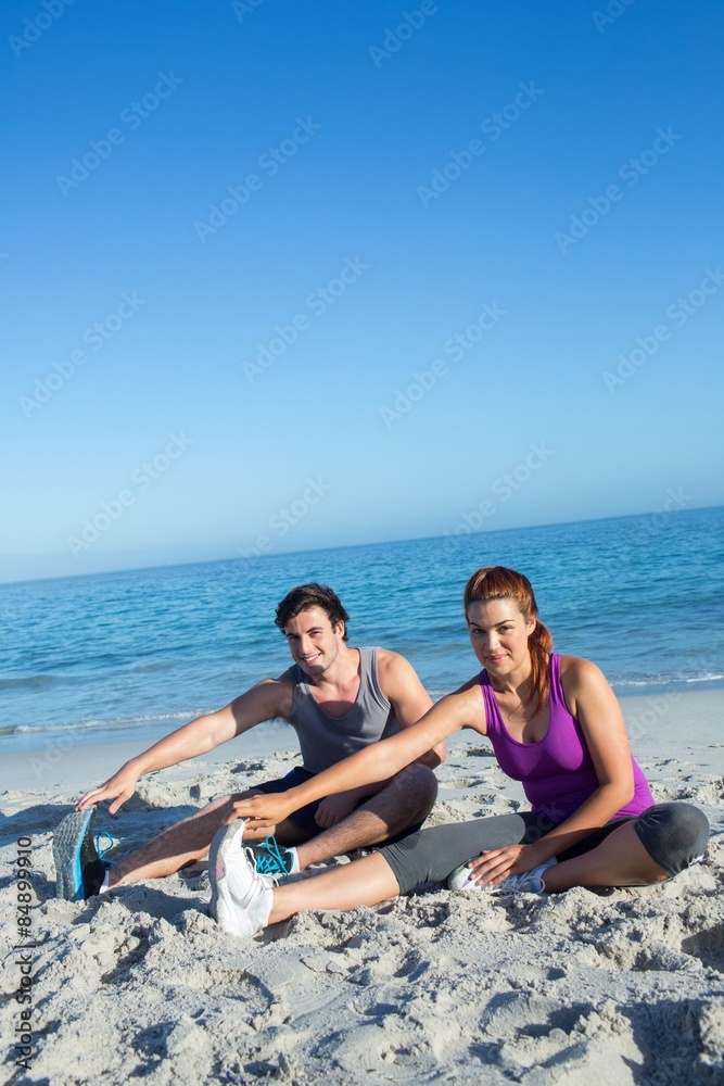 Fototapeta premium Happy couple stretching together beside the water