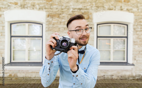 happy young hipster man with film camera in city
