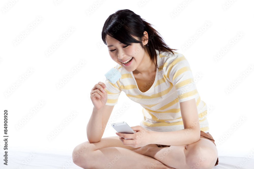 アイスを食べる女性 笑顔でスマートフォンを操作 アイスを食べる女性 笑顔でスマートフォンを操作