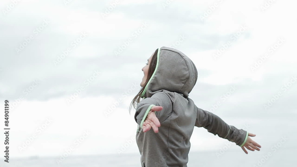 Happy woman with arms wide open standing at the beach, slow motion Happy woman with arms wide open standing at the beach, slow motion