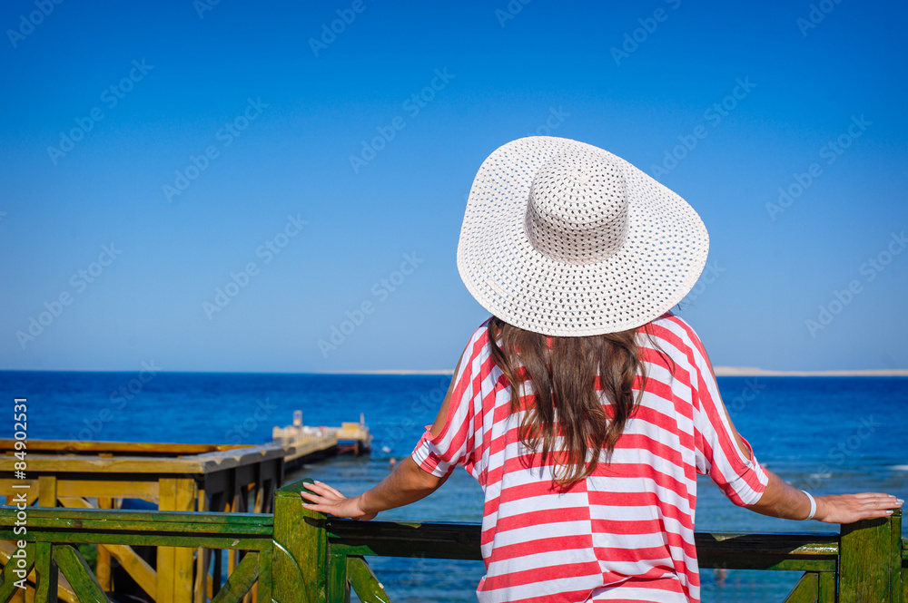 Fototapeta premium Woman in a big white hat looks at sea