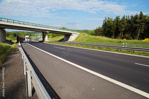 Obraz na płótnie White truck entering under a concrete bridge over a highway in a wooded landscape w salonie