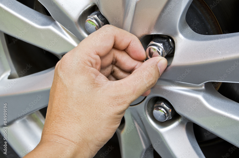 Fototapeta premium Replacing lug nuts by hand while changing tires on a vehicle.