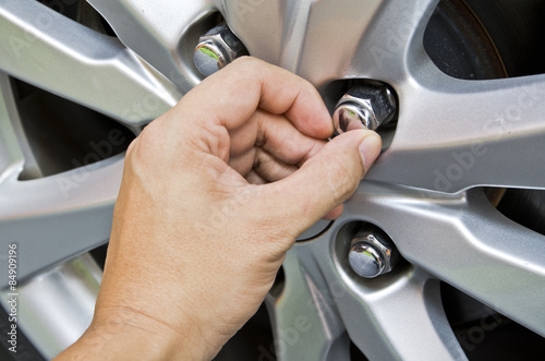 Replacing lug nuts by hand while changing tires on a vehicle.