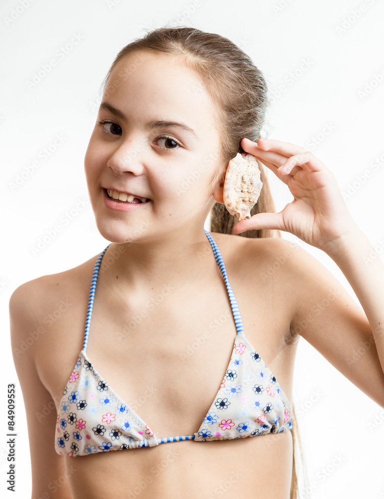 smiling girl posing with seashell next to ear smiling girl posing with seashell next to ear