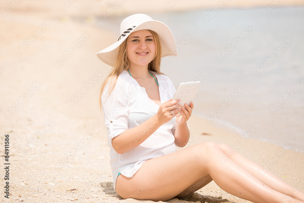 smiling woman sitting on sandy beach with digital tablet smiling woman sitting on sandy beach with digital tablet