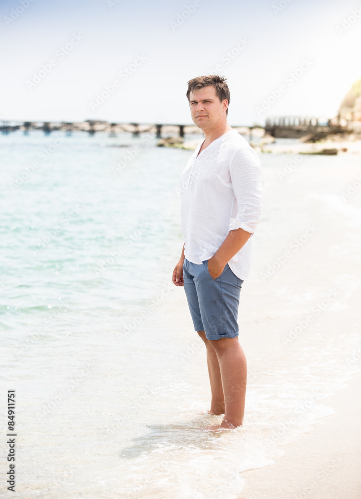 stylish man in shirt and shorts standing on the beach stylish man in shirt and shorts standing on the beach