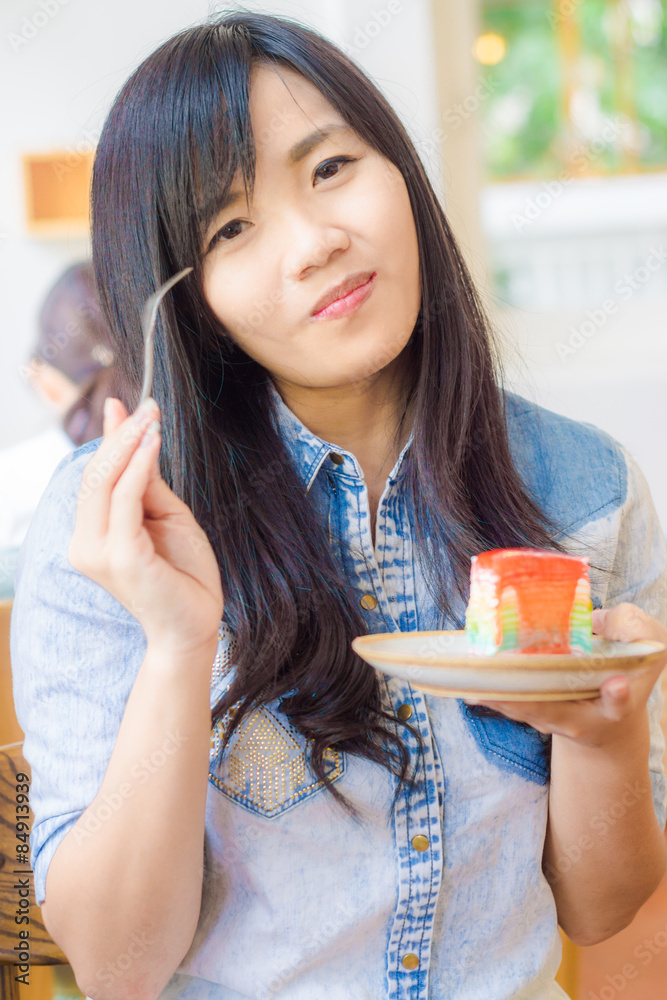 Asian smiling woman wearing jean shirt biting the piece of tasty Asian smiling woman wearing jean shirt biting the piece of tasty