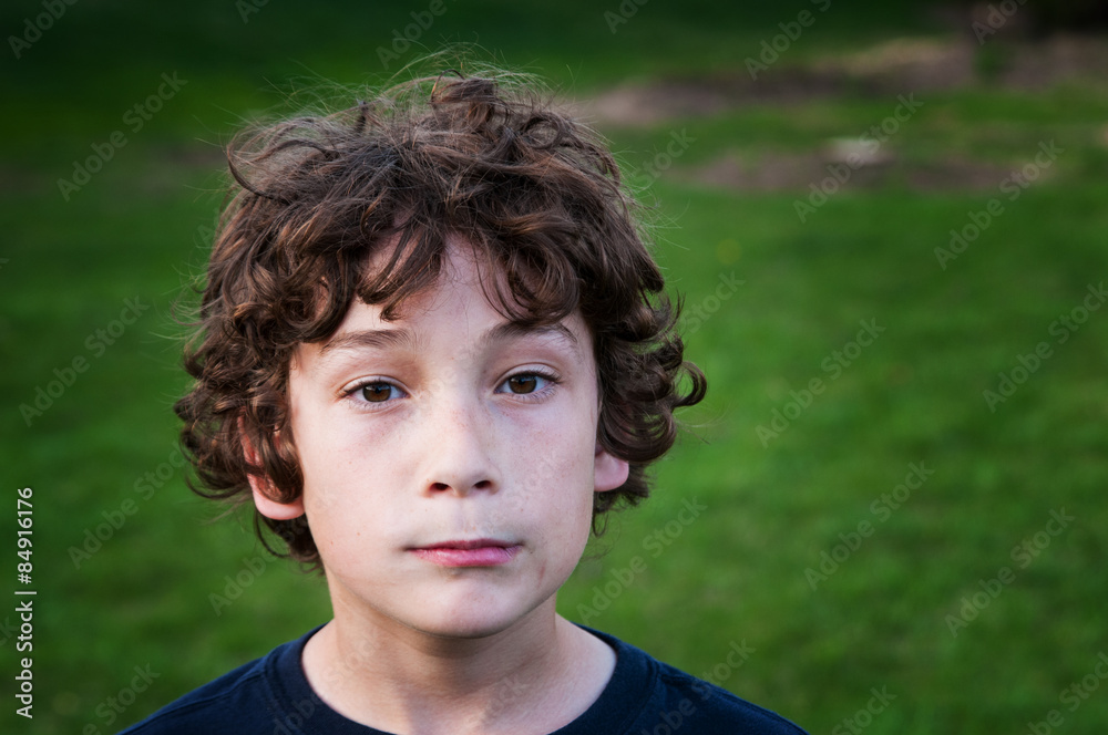 young brown haired boy outdoors on a green grassy yard young brown haired boy outdoors on a green grassy yard