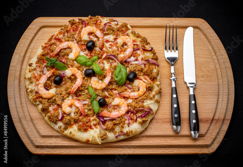 Tuna pizza with shrimp and black olives, cutlery
