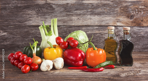 Fototapeta Naklejka Na Ścianę i Meble -  Colorful organic vegetables, olive oil, vinegar on wooden background 
