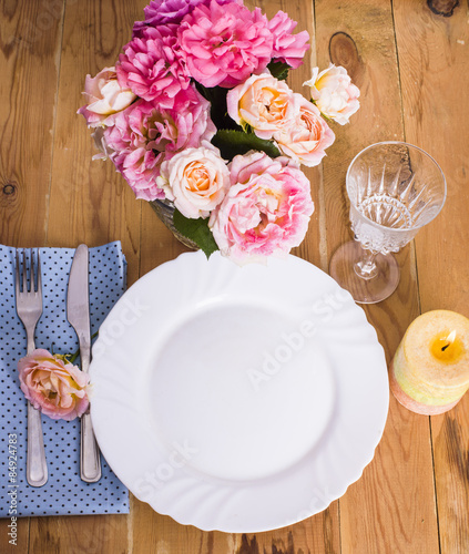Beautiful festive table setting with roses, candles and napkins 