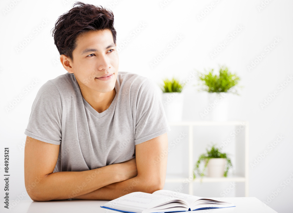 Smiling young man reading book and thinking Smiling young man reading book and thinking