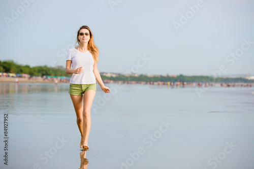 Young caucasion woman running on the beach at sunset 