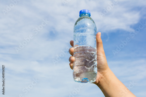hand holding water bottle on sky background