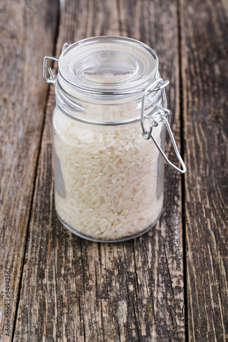 Rice in glass jar on wooden table.
